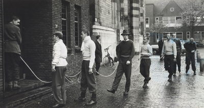 501593 Afbeelding van een aantal jongemannen (vermoedelijk studenten tijdens de ontgroening) met een touw bij het ...